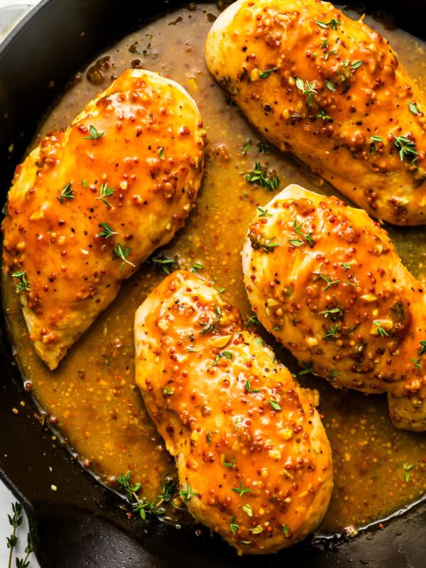 overhead view of 4 honey mustard chicken breasts in a cast iron skillet.