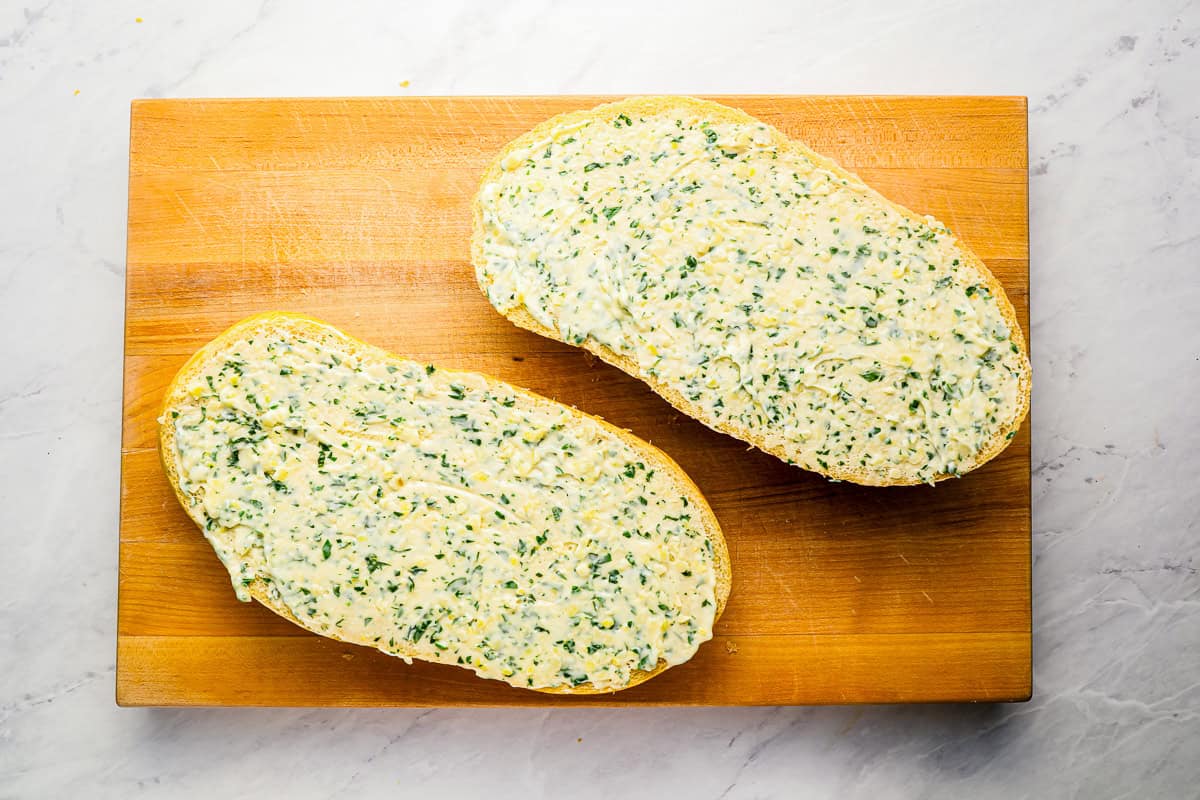 2 pieces of garlic bread on a cutting board.