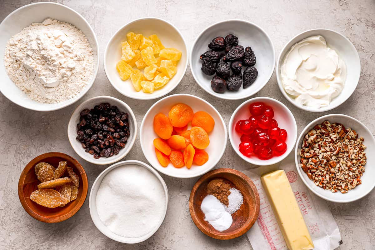 Ingredients for homemade fruit cake, arranged in small bowls.