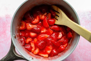 strawberry sauce in a saucepan with a wooden spoon.