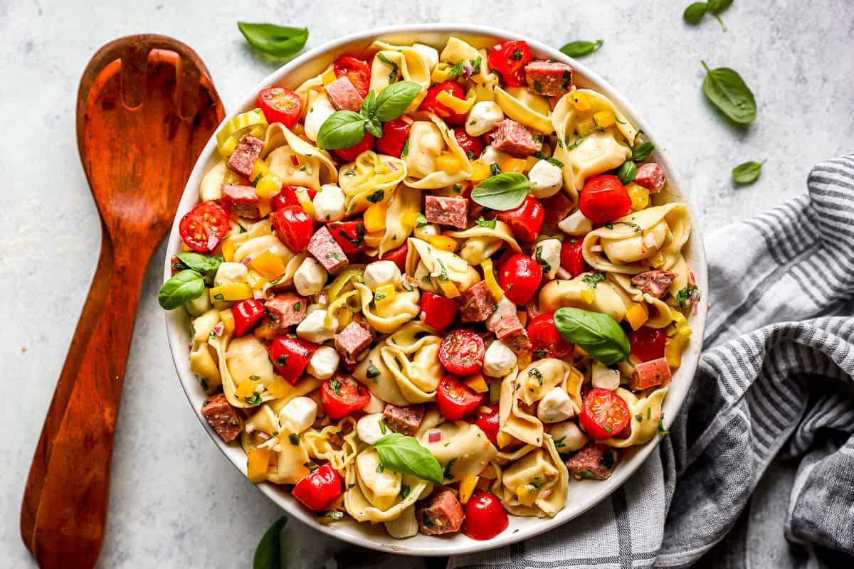 tossed tortellini pasta salad in a white serving bowl.