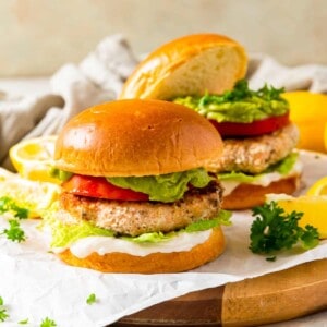 salmon burger on a bun topped with tomato, lettuce, guacamole