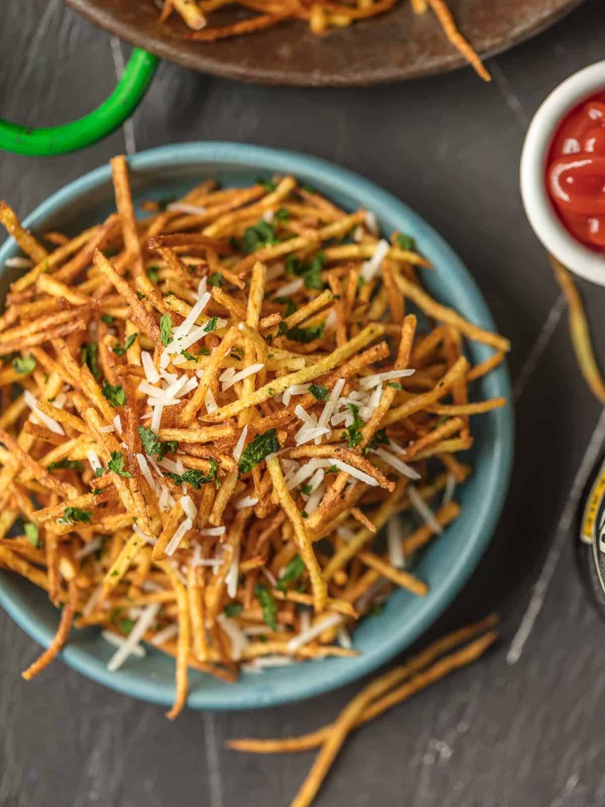 Shoestring Potatoes piled in a blue bowl.