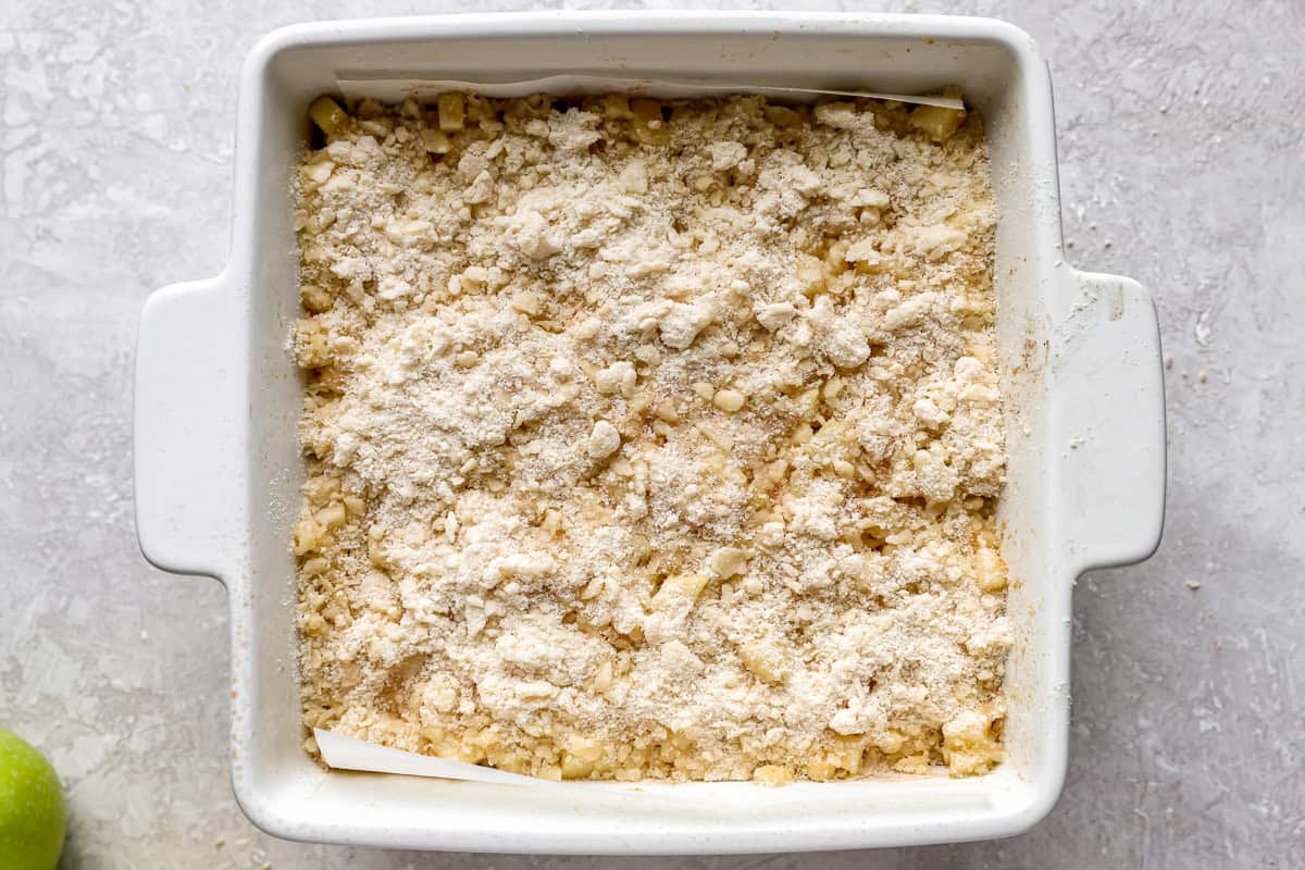 crumb topping over apple pie bars in a square baking dish.