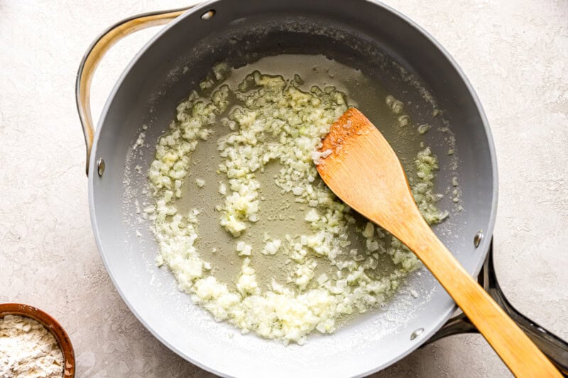 sauteeing onion in a pan with a wooden spoon.