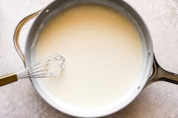 thick and creamy white sauce in a pan with a whisk.