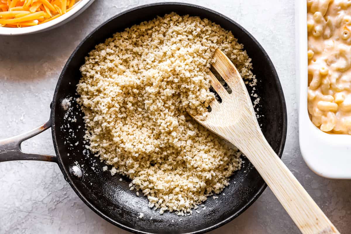 toasting breadcrumbs in a pan with a wooden spoon.