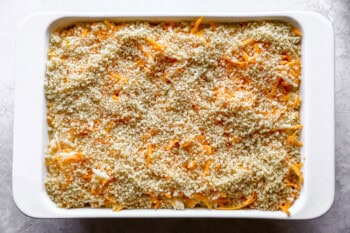 breadcrumbs and cheese sprinkled over mac and cheese in a casserole dish.