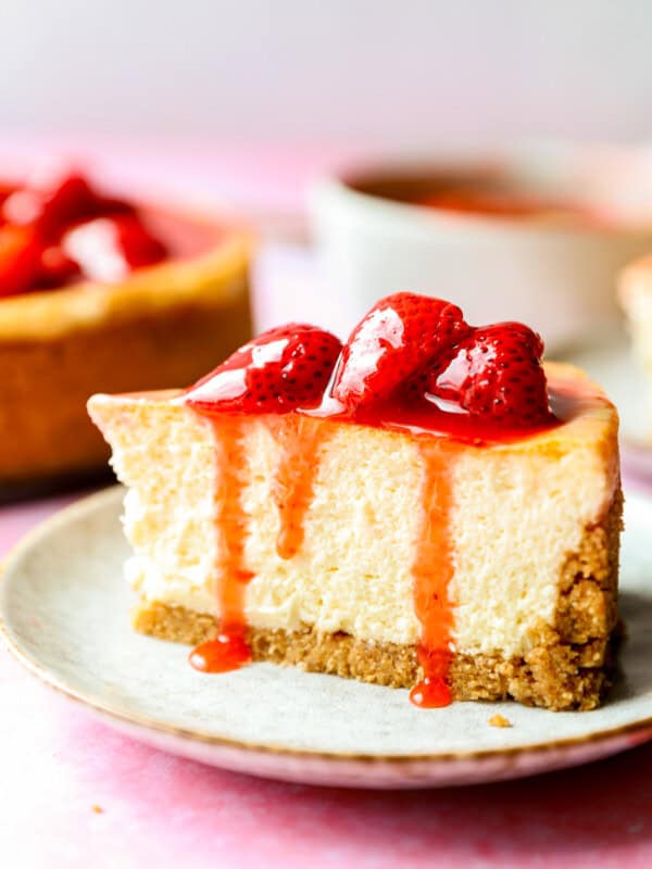 side view of a slice of cheesecake with strawberry sauce on top.