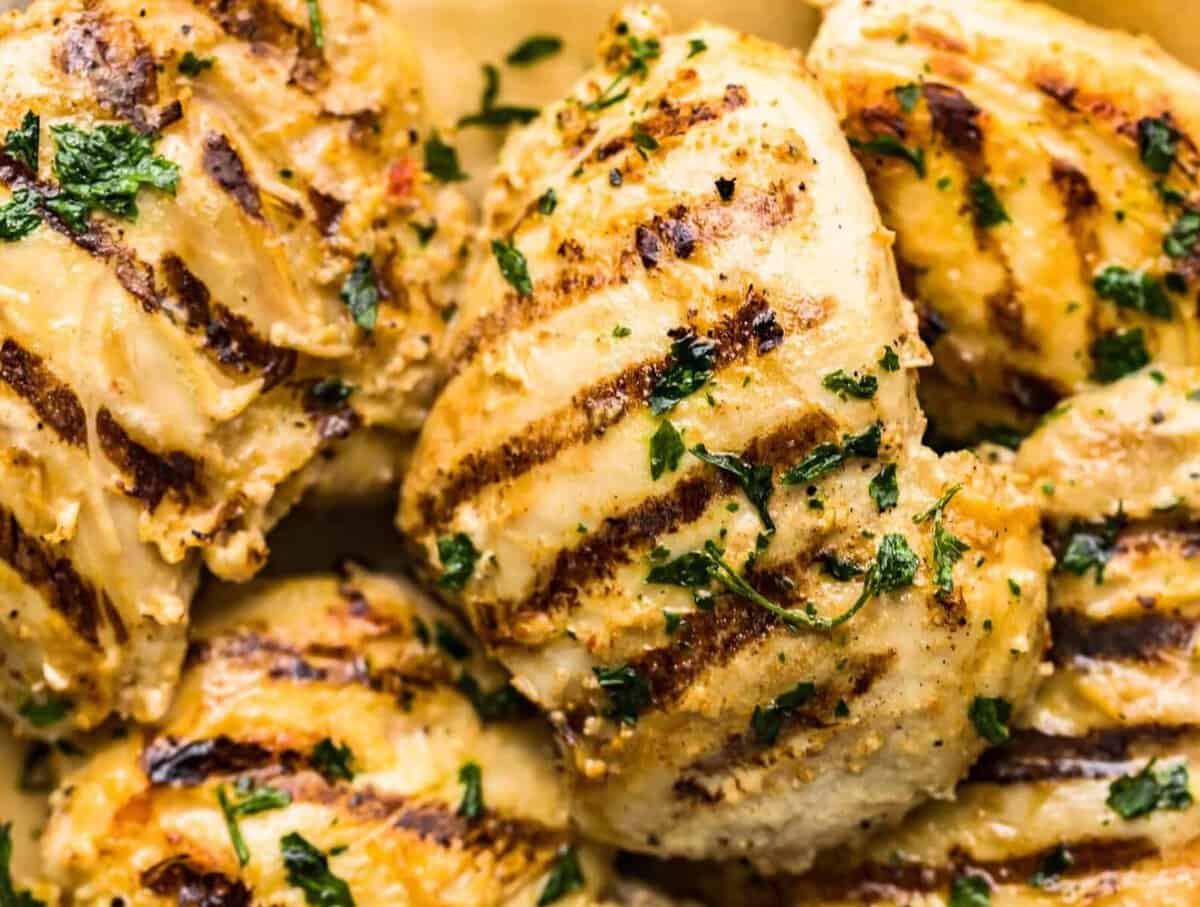 Grilled yogurt-marinated chicken on a plate with herbs.