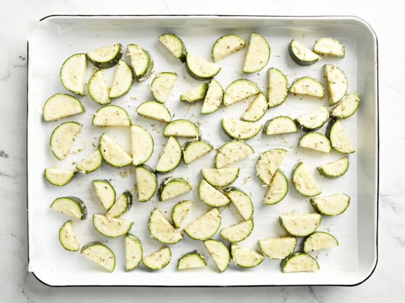 seasoned zucchini slices on a parchment-lined baking sheet.