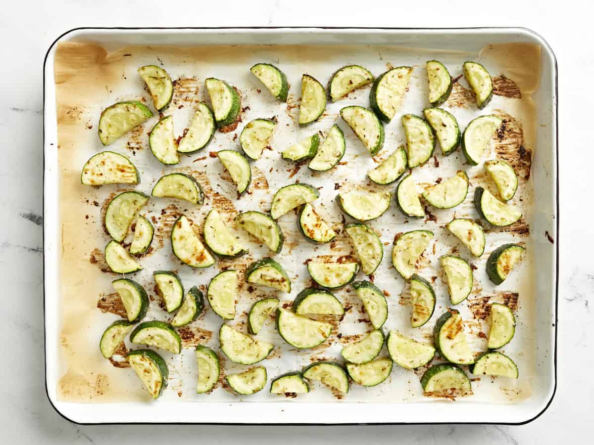 roasted zucchini slices on a parchment-lined baking sheet.