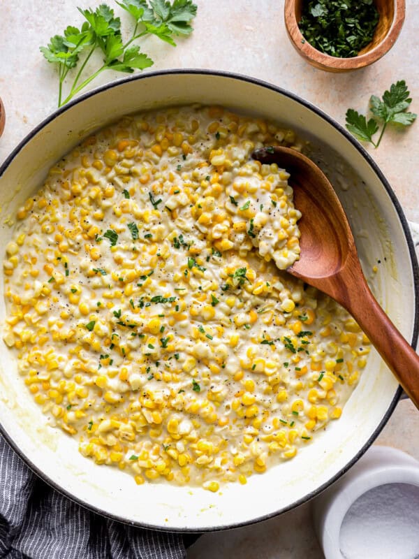 overhead view of creamed corn in a dutch oven with a wooden spoon.