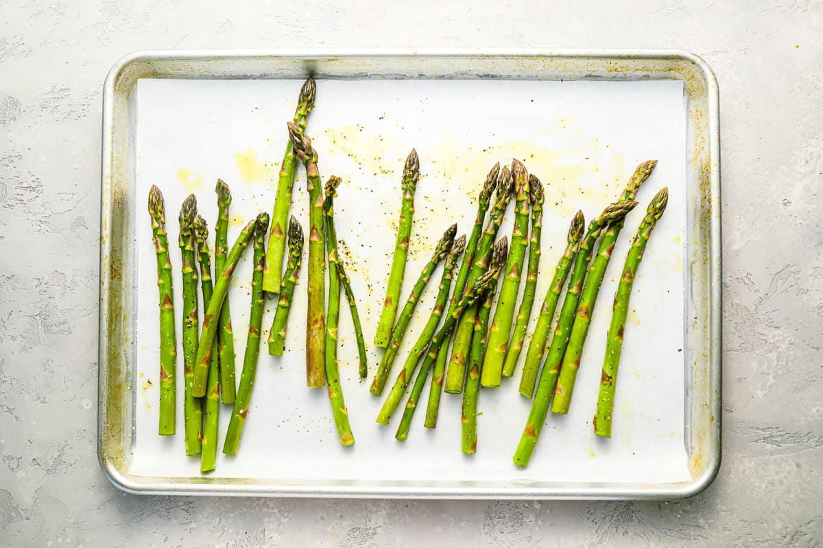 trimmed seasoned asparagus on a parchment-lined baking sheet.