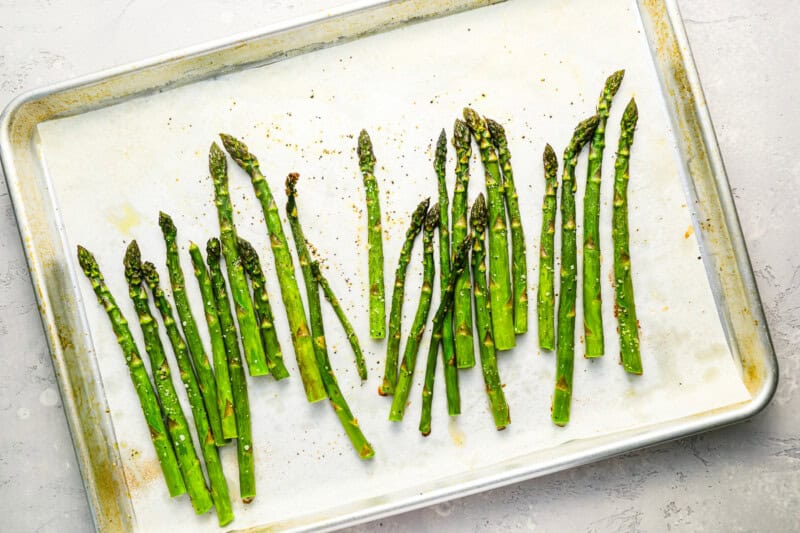 baked asparagus on a parchment-lined baking sheet.