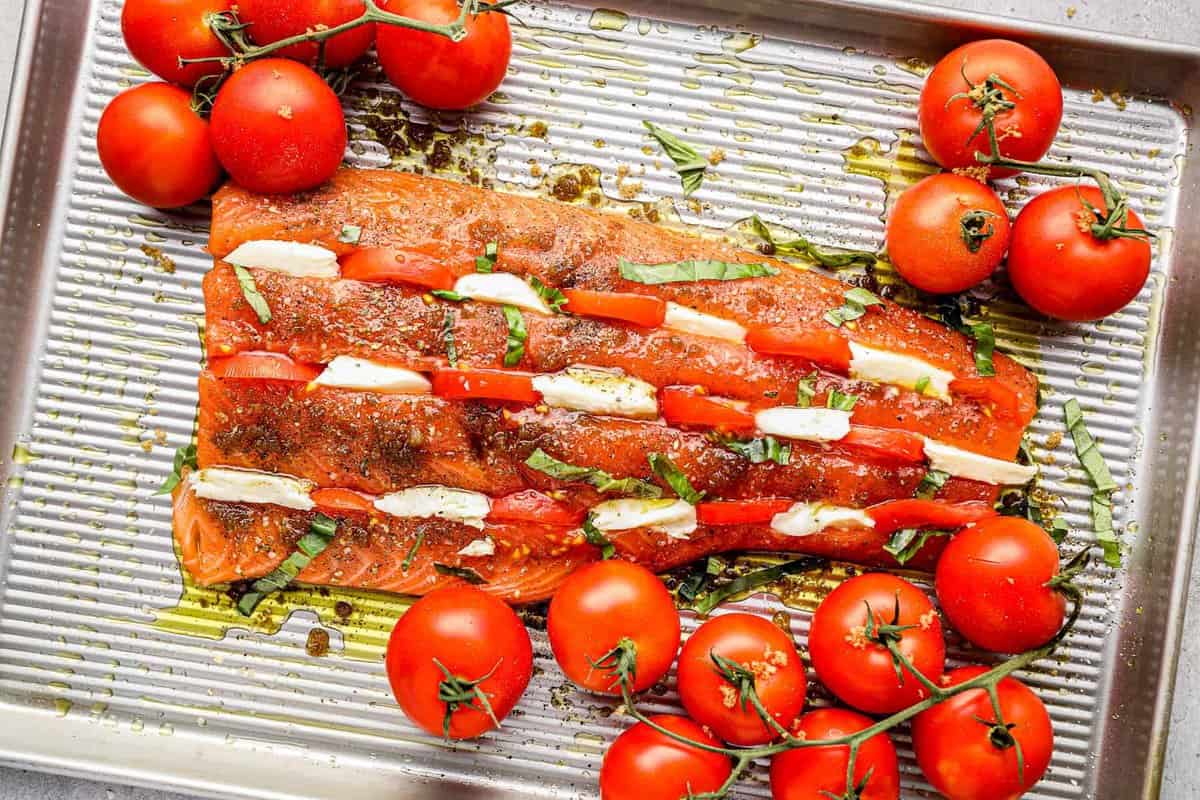 Unbaked salmon filet stuffed with pieces of tomato and mozzarella.