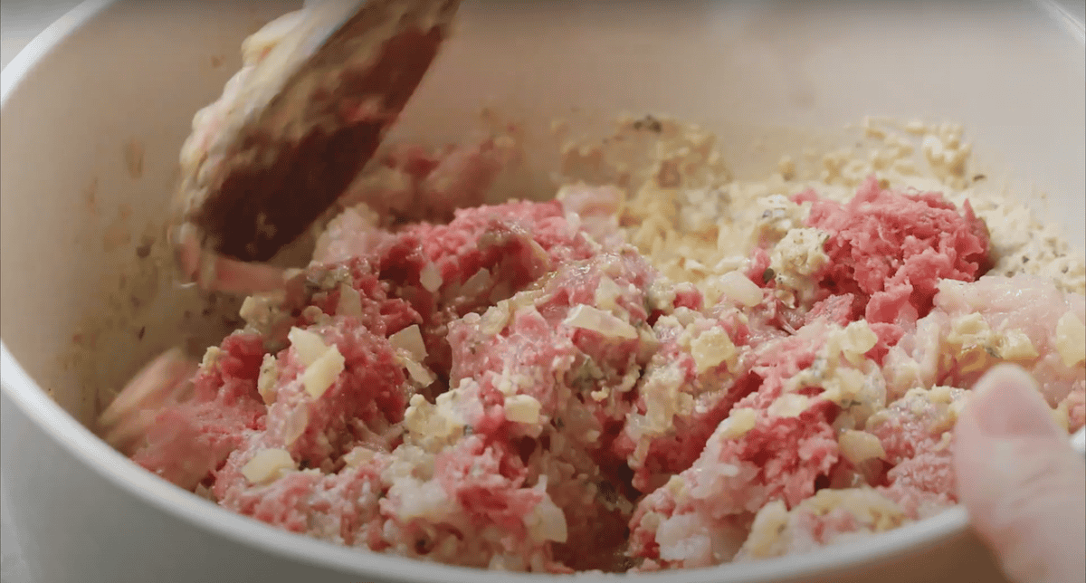 Mixing ground meat into a breadcrumb mixture.