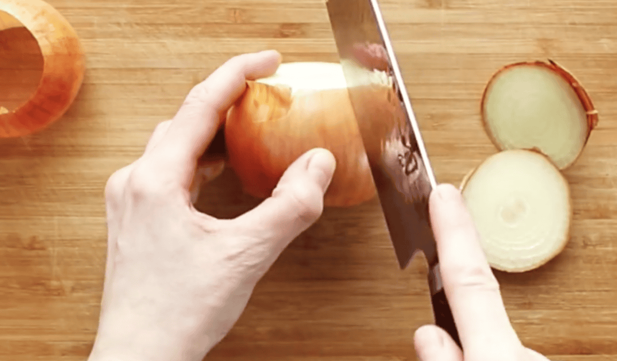 Slicing into an onion to help remove the papery skins.