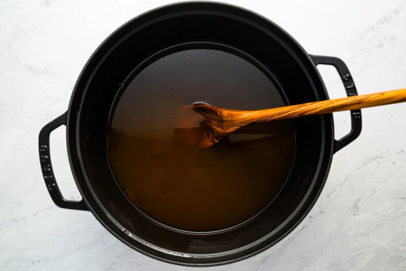 clear, pulp-free apple cider in a pot with a wooden spoon.