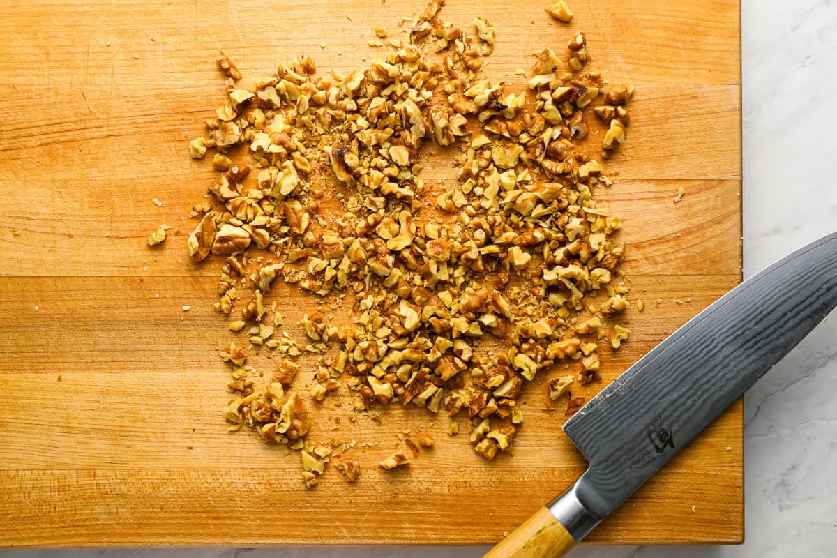 chopped nuts on a cutting board with a knife.