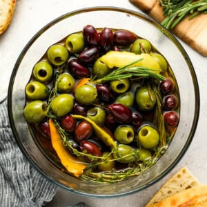 overhead view of marinated olives in a glass bowl.