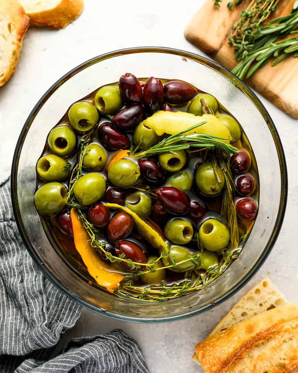 overhead view of marinated olives in a glass bowl.