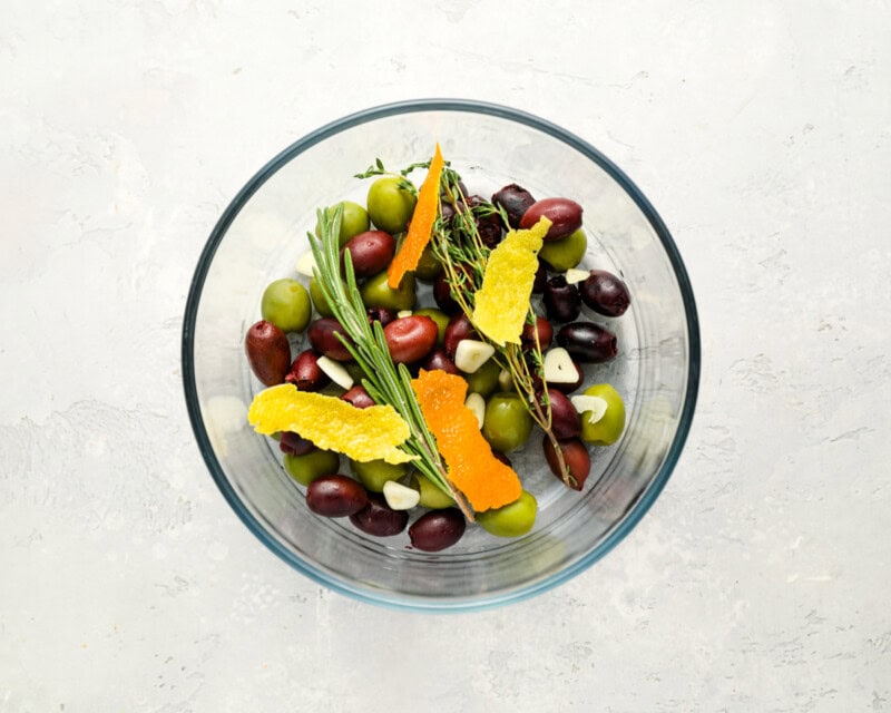 olives, herbs, spices, and garlic in a glass bowl.