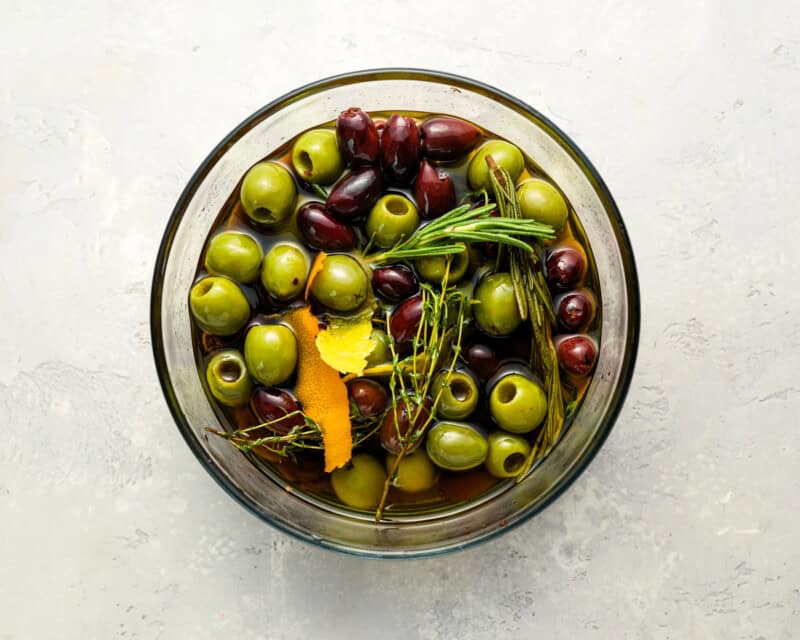 overhead view of marinated olives in a glass bowl.