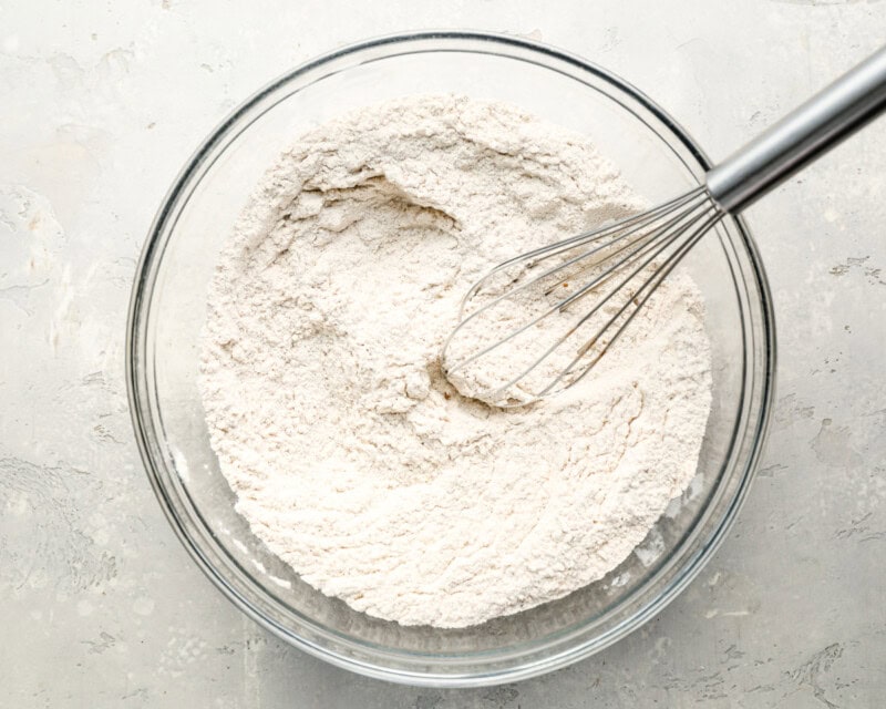 flour in a glass bowl with a whisk.