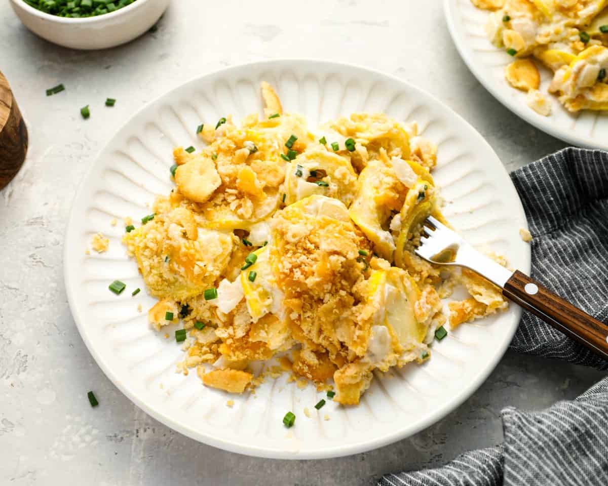 a serving of squash casserole on a white plate with a fork.