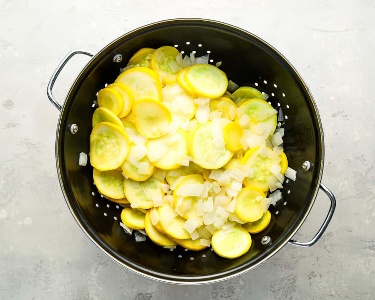 draining cooked yellow squash in a colander.