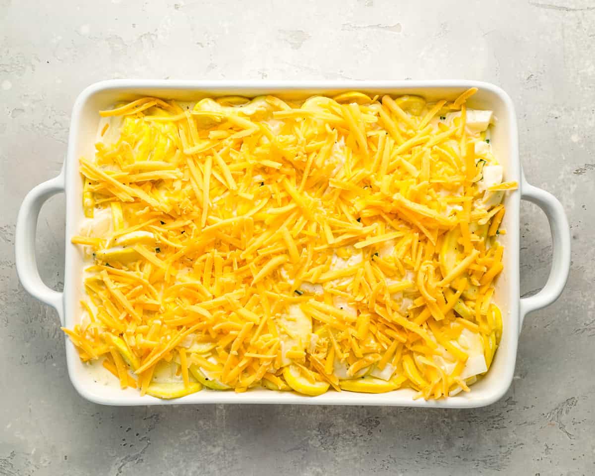 squash casserole topped with cheese in a baking dish.