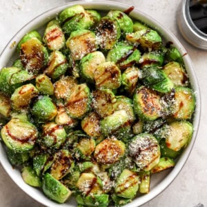 overhead view of garlic parmesan brussels sprouts in a bowl with balsamic drizzle.