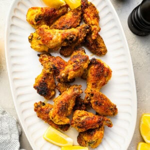 a bunch of lemon pepper wings on a white platter in an overhead shot