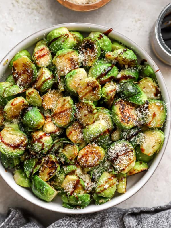 overhead view of garlic parmesan brussels sprouts in a bowl with balsamic drizzle.