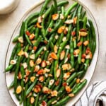 overhead view of green beans almondine on an oval platter.