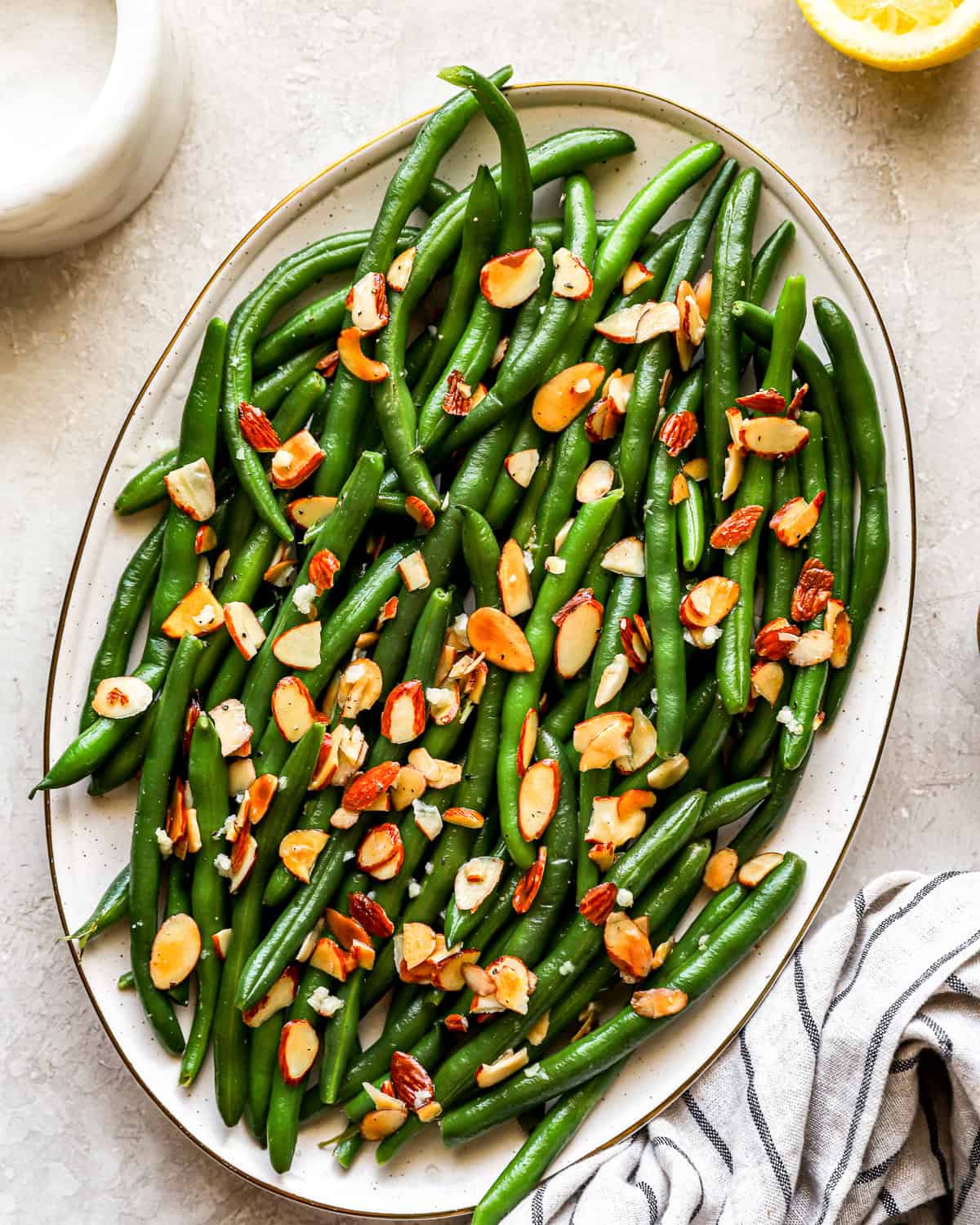 overhead view of green beans almondine on an oval platter.