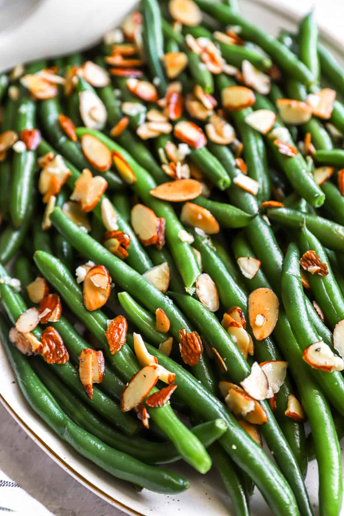 closeup of green beans almondine on a white platter.