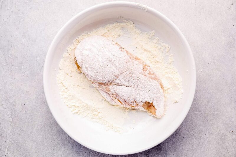 chicken breast coated in flour on a white plate