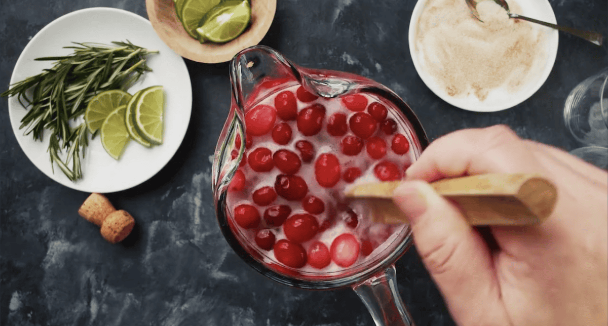 Stirring cranberries in a pitcher of jingle juice.