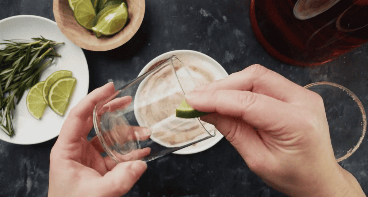 Wetting the rim of a glass with lime juice.