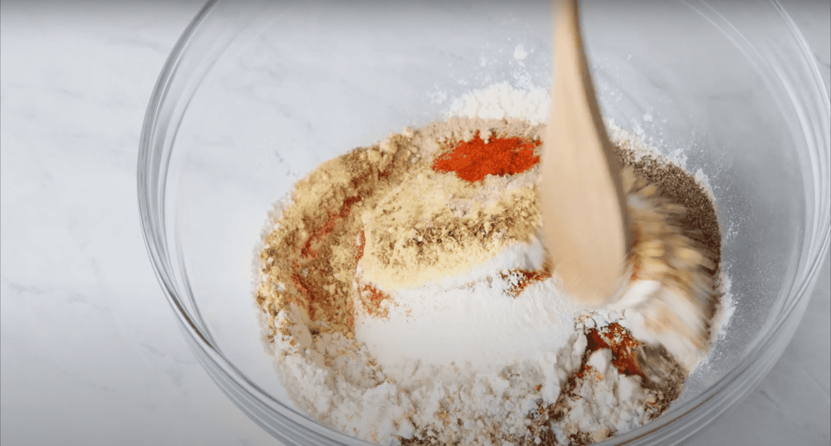 Mixing flour and kfc spices in a bowl.