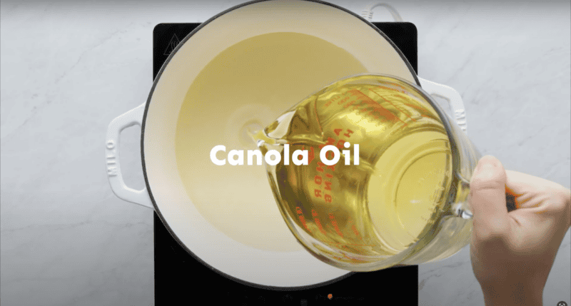 Pouring canola oil into a Dutch oven.