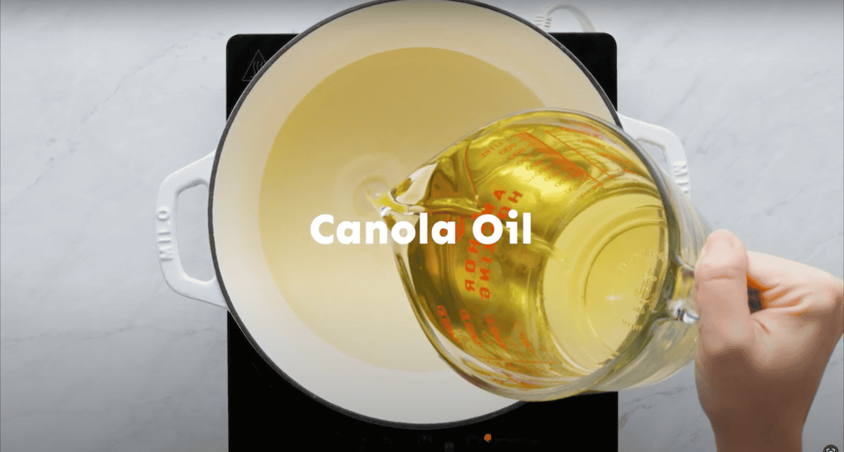 Pouring canola oil into a Dutch oven.