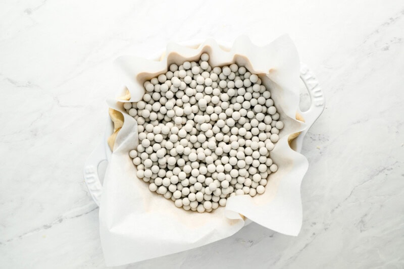 fluted pie dough lined with parchment and filled with pie weights.