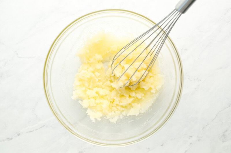 whisking butter and sugar in a glass bowl.