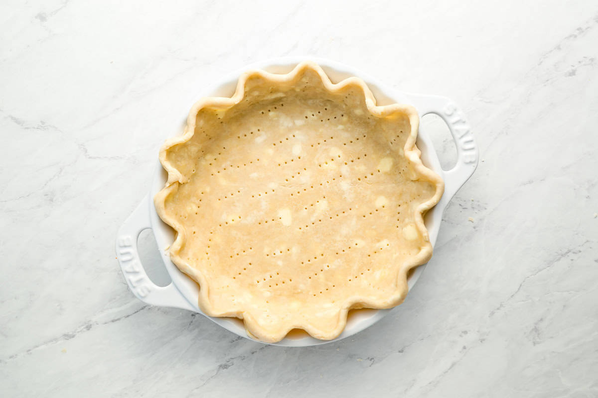 pricked fluted pie dough in a pie pan.