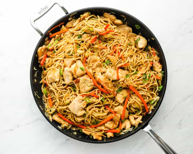 stir fry noodles with chicken and veggies in a black skillet