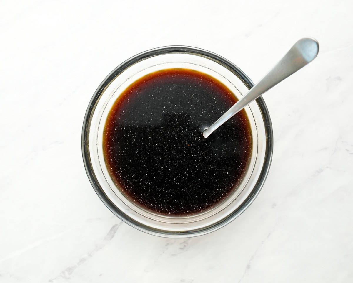 dark brown sauce in small clear bowl with metal spoon