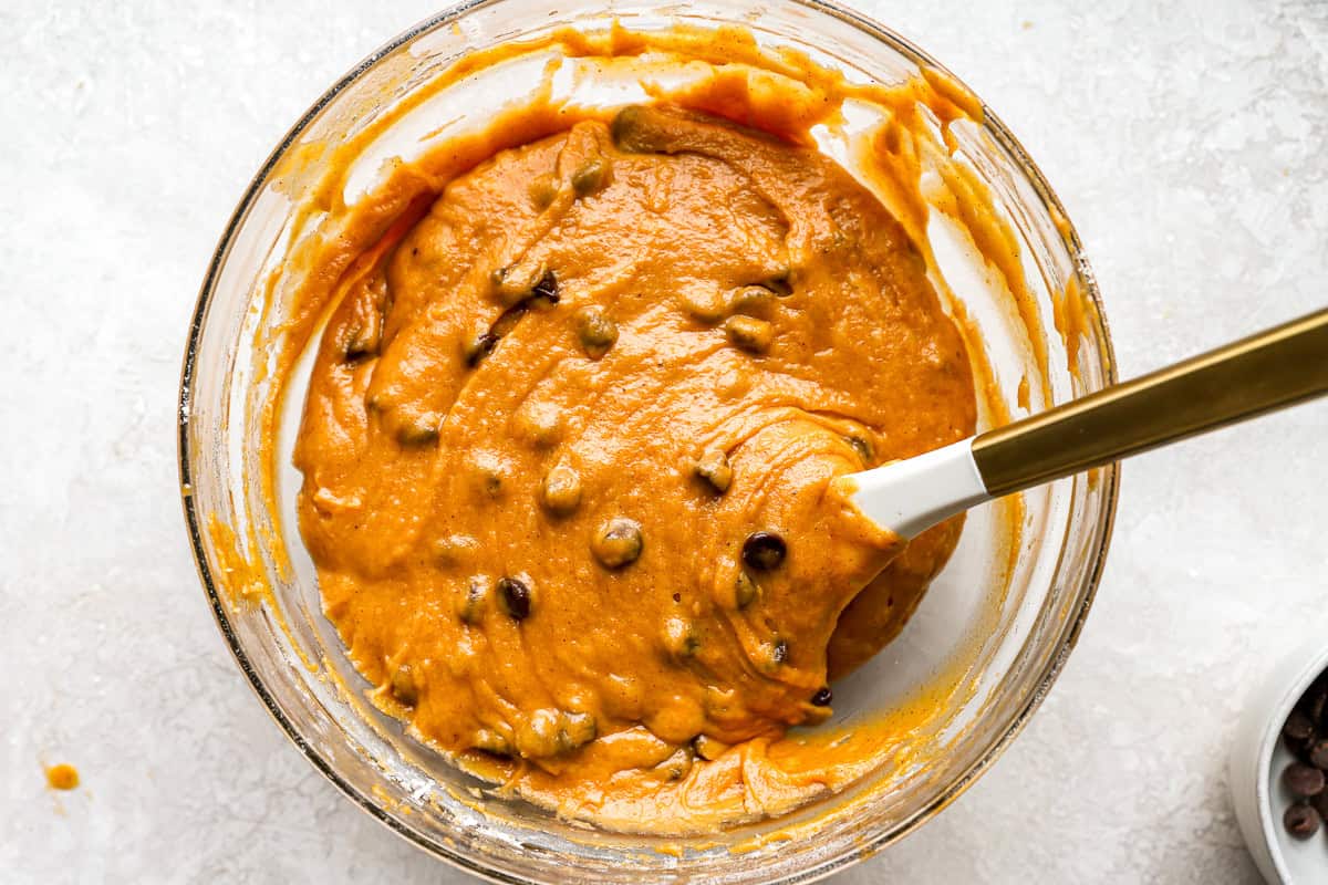 chocolate chip pumpkin cookie bar batter in a glass bowl with a rubber spatula.